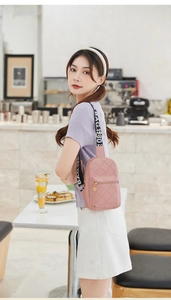 Close-up of pink quilted crossbody bag with BAG.1980 strap and gold zipper charm