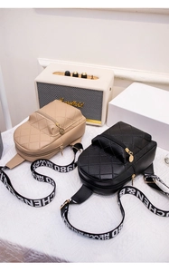 Detail of diamond quilted crossbody bags in beige and black with wide lettered straps