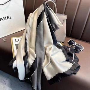 Elegant geometric print silk scarf in black and grey draped on a luxury leather sofa