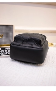 Detail view of the quilted rhombic texture and fashion strap on black crossbody bag