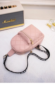 Close-up of pink quilted chest bag with golden zipper and logo tag on textured background