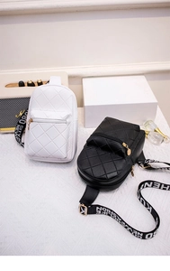 Detail of quilted leather chest bags in black and white with lettered fashion straps