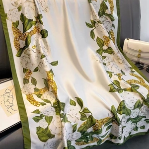 Luxuriöses Seidenschal-Design mit weißen Kamelien und Goldketten-Muster auf Sofa