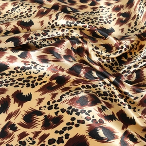 Close-up of silky leopard print fabric showing smooth satin texture and glossy finish