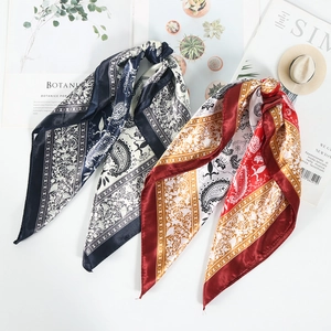 Flat lay of silk square scarves with paisley prints in navy and burgundy floral designs