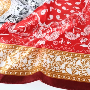 Macro shot of red paisley silk scarf showing satin texture and golden pattern details