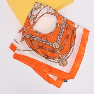 Detail of orange chain print satin scarf with equestrian motif next to gift box