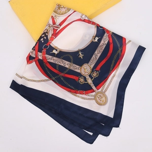 Detail of navy silk scarf with chain print and horse bit pattern on yellow box