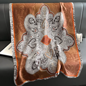 Châle vintage en satin à motifs paisley orange et marron café sur fond de cuir foncé