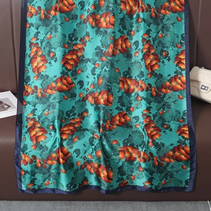 Elegante foulard in seta blu lago con motivi floreali arancioni su sfondo in pelle
