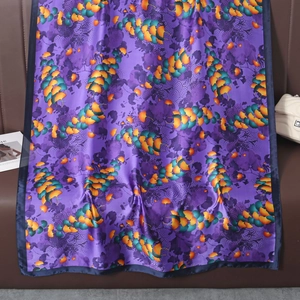 Detailed view of silk scarf texture with yellow ginkgo leaf patterns on purple satin