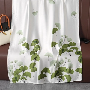 Dettaglio di sciarpa in seta con motivo a foglie di ginkgo verde su raso bianco