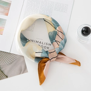 Elegant beige silk scarf with ginkgo leaf pattern styled on a minimalist magazine