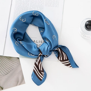 Elegant lake blue silk scarf with white horse-bit print and striped edges displayed on a table