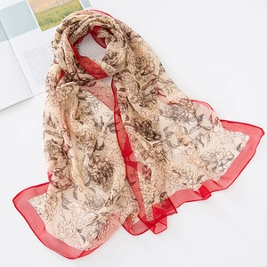 Detalle de bufanda de seda georgette con estampado floral marrón y borde rojo