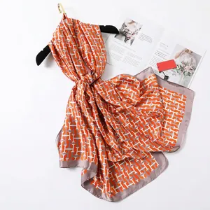 Longue écharpe en soie satinée à imprimé H orange et blanc avec un drapé élégant et fluide
