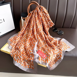 Écharpe de soie orange à la mode avec imprimé de lettres H élégamment drapée sur un sac