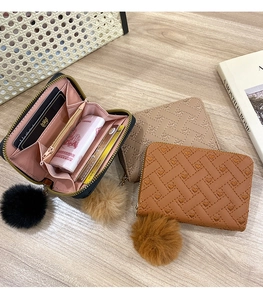 Detail view of woven leather coin purses with heart embroidery and plush ball charms