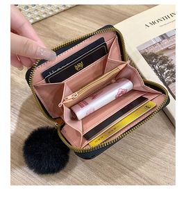 Detail view of mini wallet with pink interior slots and black faux fur pompom keychain