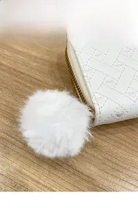 Detail of white woven leather coin purse featuring heart textures and a fluffy wool ball charm