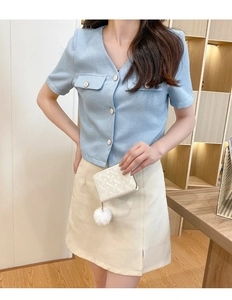 Short-sleeved light blue knit top paired with white skirt and a small crossbody bag