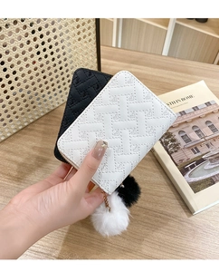 Detail of heart-quilted PU leather coin purse with fluffy pompom and gold chain