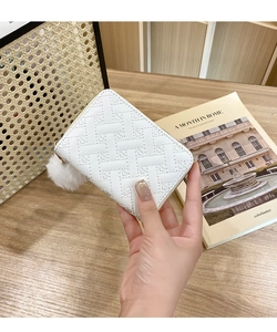 Close-up of white quilted leather card holder with gold zipper and plush ball charm