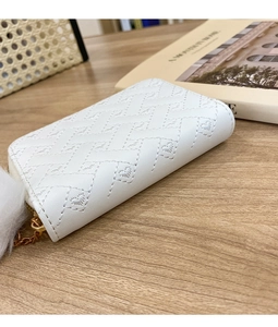 Close-up of white heart-quilted coin purse with golden zipper and fluffy pompom charm