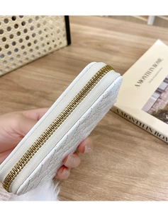 Close-up of white quilted leather wallet featuring gold zipper detail and fine texture