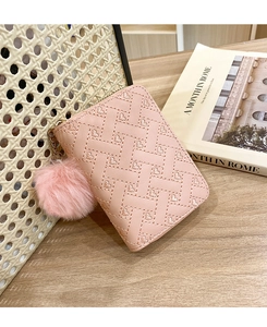 Close-up of pink woven leather wallet with heart details and a fluffy pompom keychain