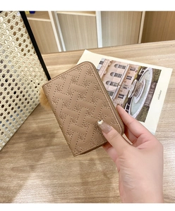 Detail of beige woven texture wallet with heart patterns and a soft fur ball keychain