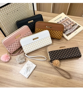 Flat lay of multiple color long zip-around wallets with pompom charms on wooden background