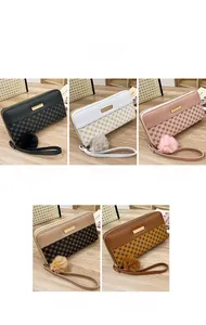 Close-up of color-block long wallets with furry ball charms and wristlet straps