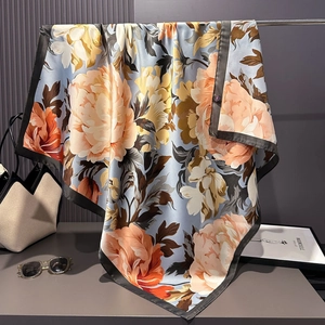 Detail of silk-satin scarf featuring orange peonies and navy blue border hung elegantly