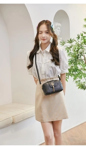 Detail of black embossed PU crossbody bag with golden crown buckle and tassel