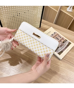 Detailed view of women's long floral wallet with yellow patterns and plush ball pendant