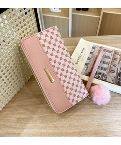 Close-up of pink leather wallet with clover patterns and a fluffy pom-pom charm