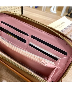 Macro shot of long leather wallet interior with multiple card slots and pink zipper pocket
