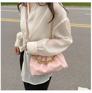 Détail d'un sac plissé rose avec chaîne dorée épaisse et bandoulière en cuir