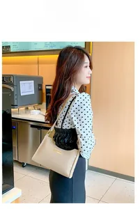 Close-up of beige woven leather shoulder bag with golden metal buckle and zipper detail