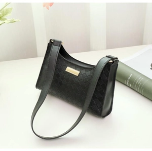 Detailed close-up of black woven leather texture and golden metal buckle on the shoulder bag