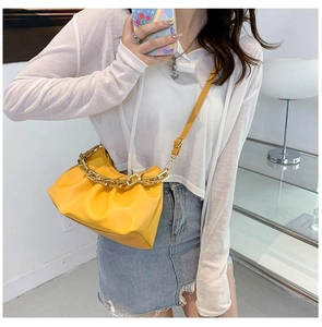 Détail du sac nuage plissé jaune avec chaîne dorée épaisse et bandoulière en cuir