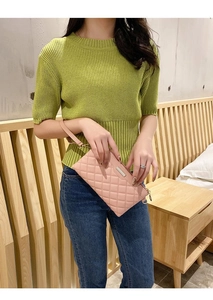 Pochette matelassée rose avec dragonne, tenue par un mannequin en tricot vert doux