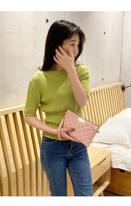 Détail de la pochette matelassée rose avec logo doré portée au poignet par un mannequin