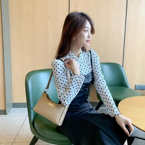 Elegant beige leather underarm bag with gold metal plaque shown on a model in a city chic style