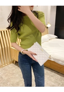 Détail d'une pochette blanche matelassée avec plaque dorée et dragonne en similicuir