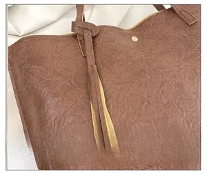 Détail du sac cabas marron avec pompon décoratif et texture en cuir souple effet vintage
