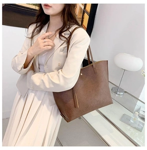 Sac cabas marron à texture vintage et détail de gland, porté par un mannequin en studio