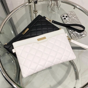 Pochette élégante avec motif matelassé, bordure métallique et dragonne en noir et blanc