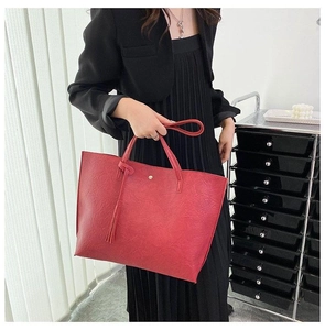 Détail du grand sac cabas rouge avec pampille et texture froissée porté par un mannequin